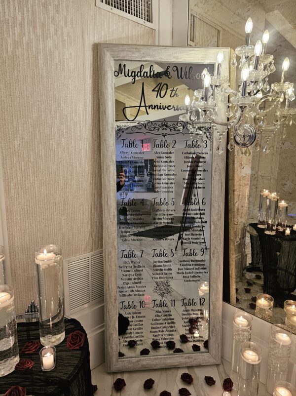 Migdalia and Willie's 40th Anniversary with guest names in black vinyl surrounded by glass cylinders with floating candles and burgundy-colored roses and runner