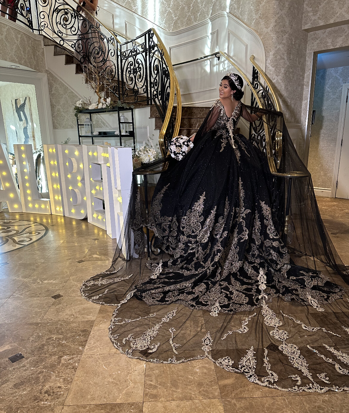 Alibeth's Quinceanera: Alibeth walking down a grand staircase and 4ft tall marquee letters that spell out ALIBETH with warm lights in the front at the Vanderbilt in Staten Island, New York done by PMT Party Services Group