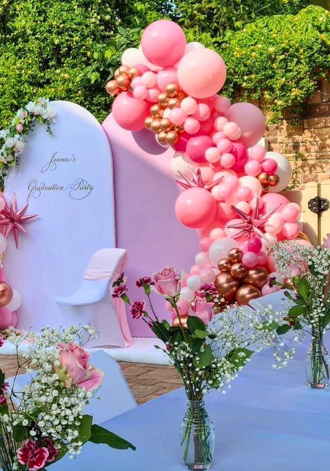 Jenna's Graduation Party Balloon Garland on 2 half arches with one white and one pink fabric and a floral arrangement in Staten Island, New York done by PMT Party Services Group